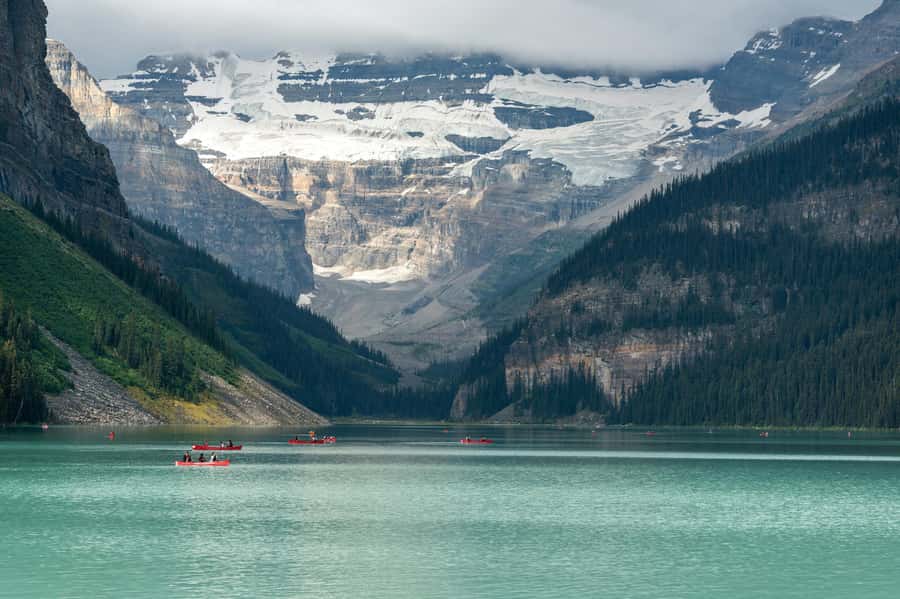 Canoes on the turquoise water of Lake Louise below the Victoria Glacier
